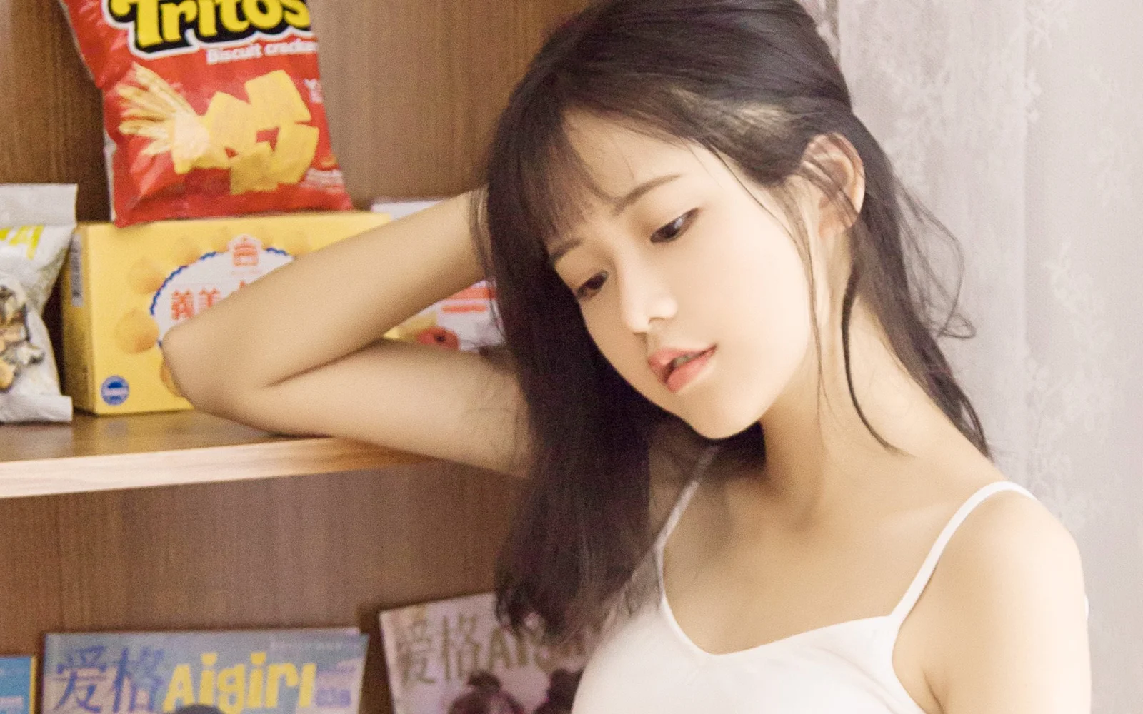 한 여성이 간식 포장이 놓인 나무 선반 옆에서 팔을 기대고 있습니다.