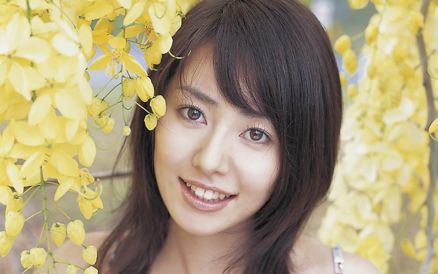 一位成年女性面带微笑，置身于盛开的黄色花朵之间。
