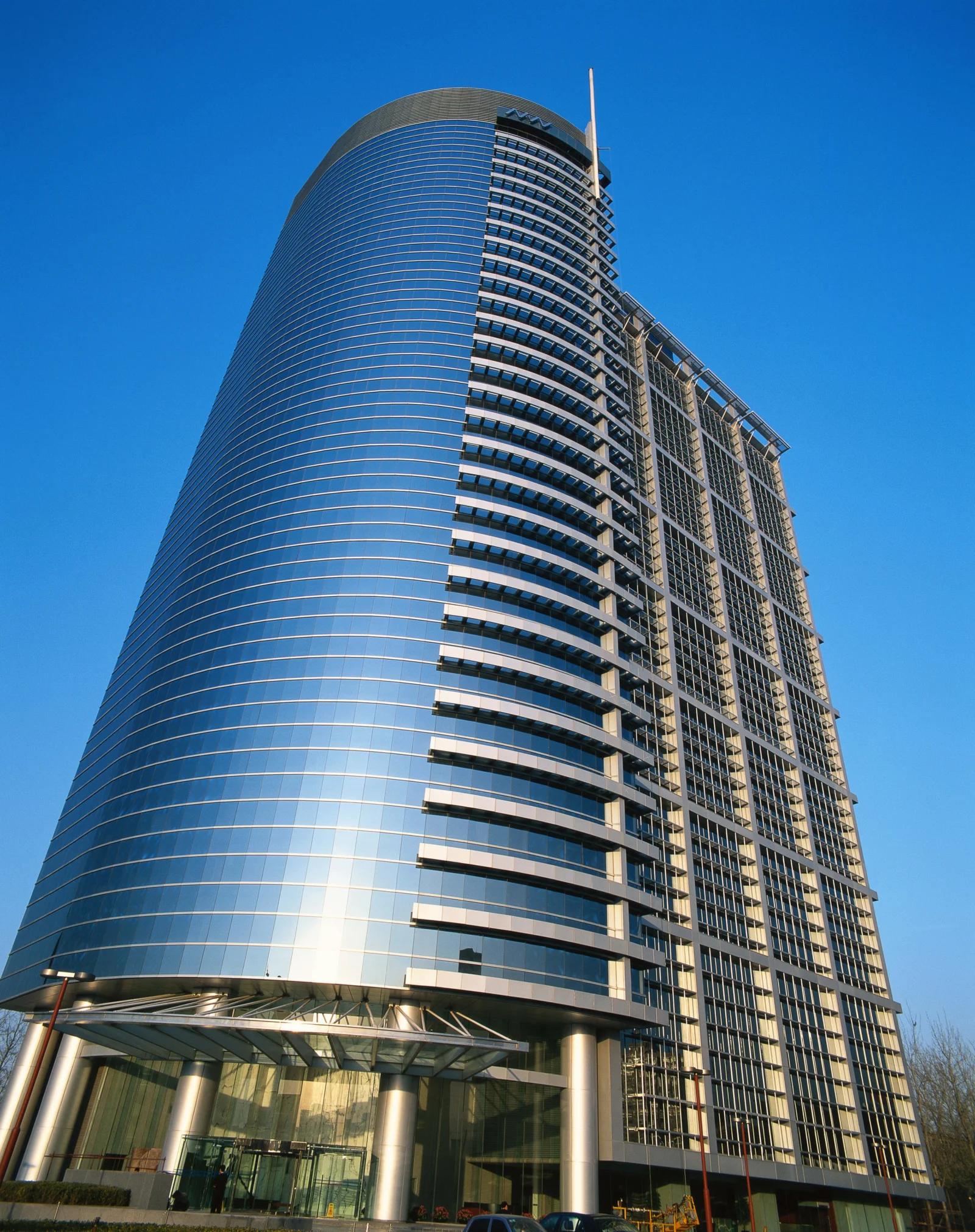 一座现代弧形高层建筑在晴朗蓝天下向上延伸。