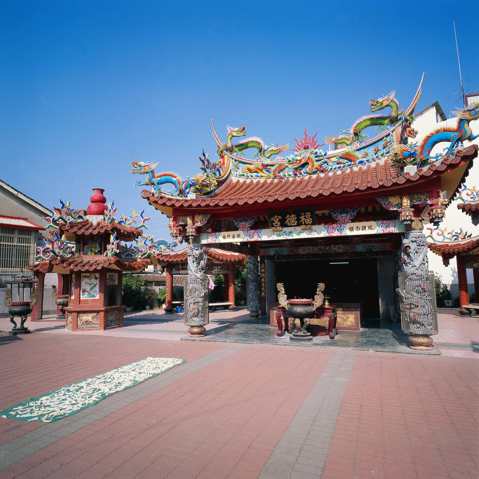 蓝天下，一座传统寺庙的彩绘屋檐、龙形装饰和宽阔庭院清晰可见。