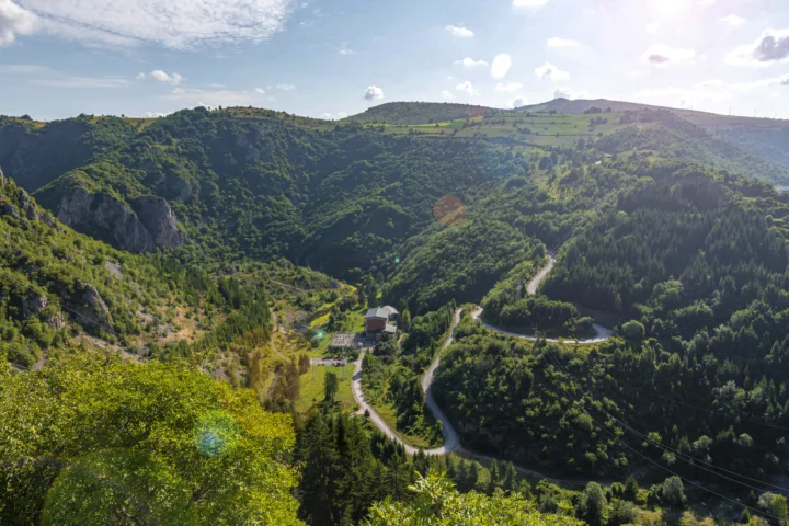 阳光照耀着层叠山脉、茂密森林和山谷中的蜿蜒道路。