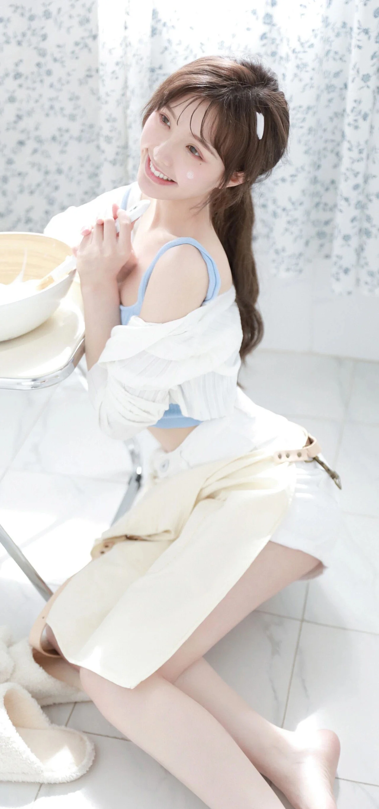 一位长发女性坐在明亮的室内空间中微笑看向镜头。