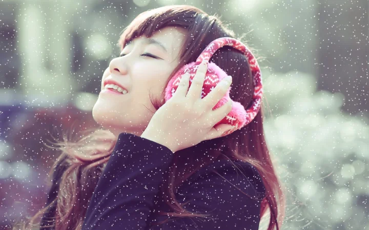 一名戴着粉色耳机的女子在飘雪般的光点中微笑聆听音乐。