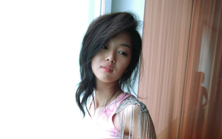 一名长发女性在室内靠近窗边的肖像照片。