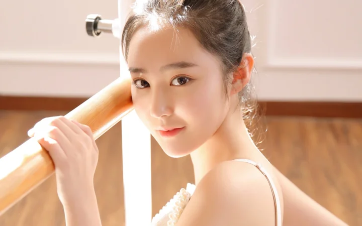一名成年女性在室内靠近木质横杆的明亮光线中回望镜头。