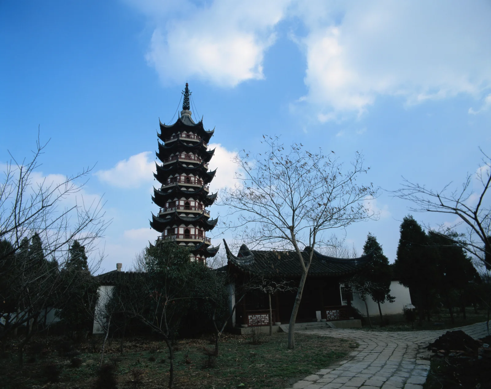 一座多层古塔矗立在传统庭院建筑与蓝天之间。