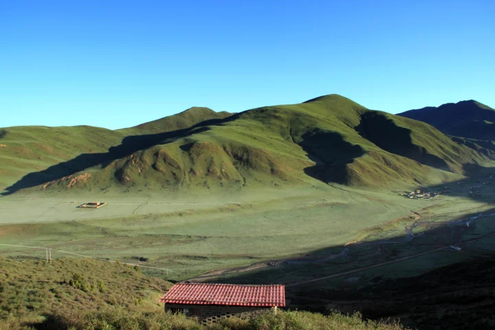 阳光照耀下的绿色山脉、开阔草原与山谷组成宁静的自然景观。
