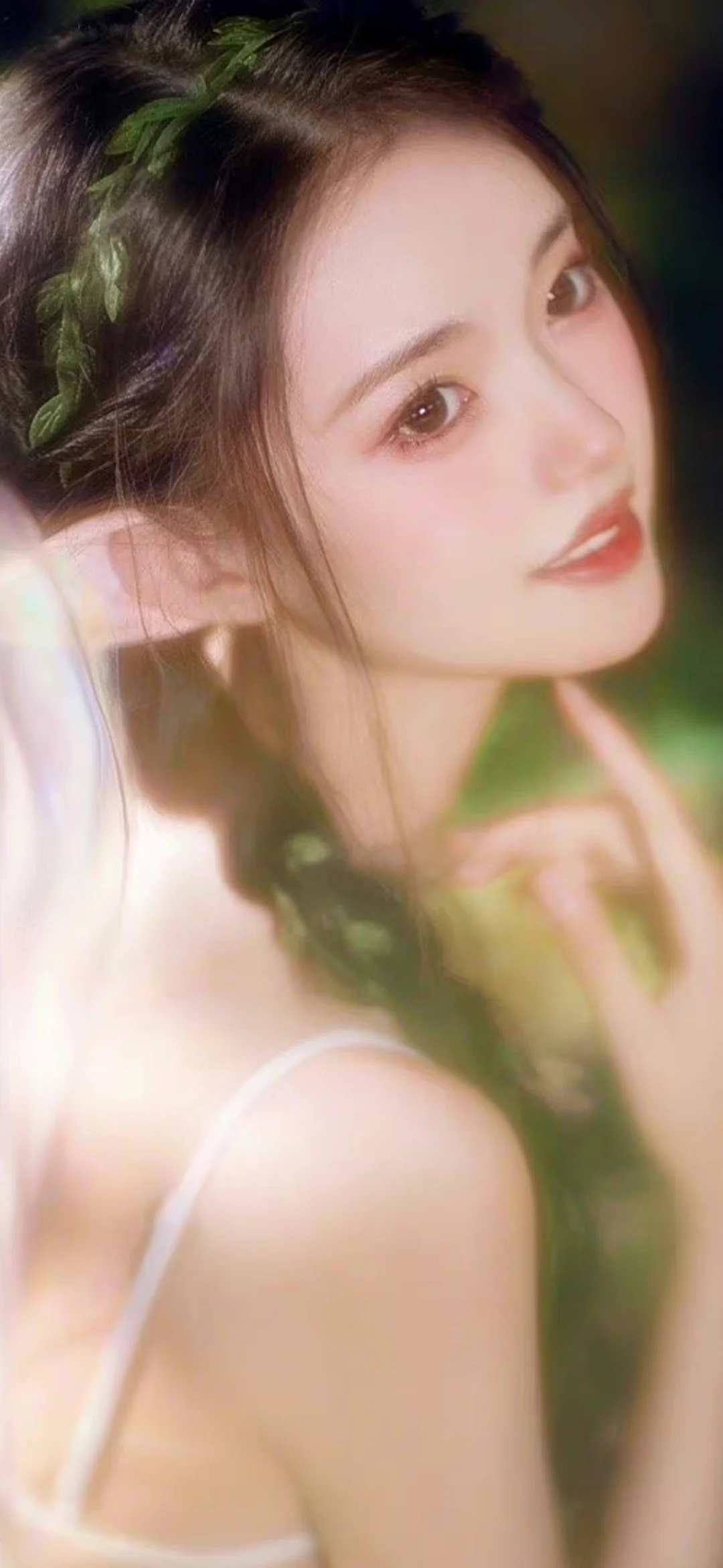一位深色长发女性在柔和光线下回眸看向镜头，背景呈现朦胧的绿色光影。