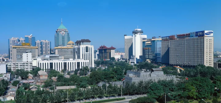 蓝天下，一片现代城市建筑群与前景绿树构成开阔的城市天际线。