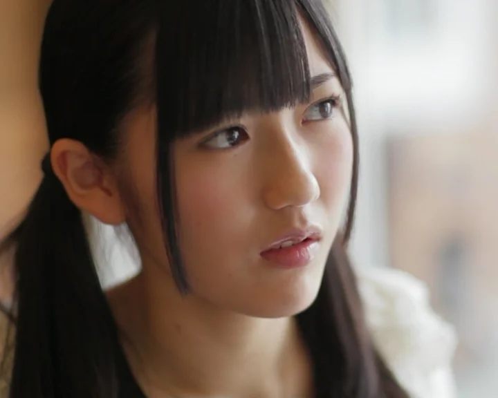 柔らかな光の中で横を見つめる黒髪の女性のクローズアップポートレート。
