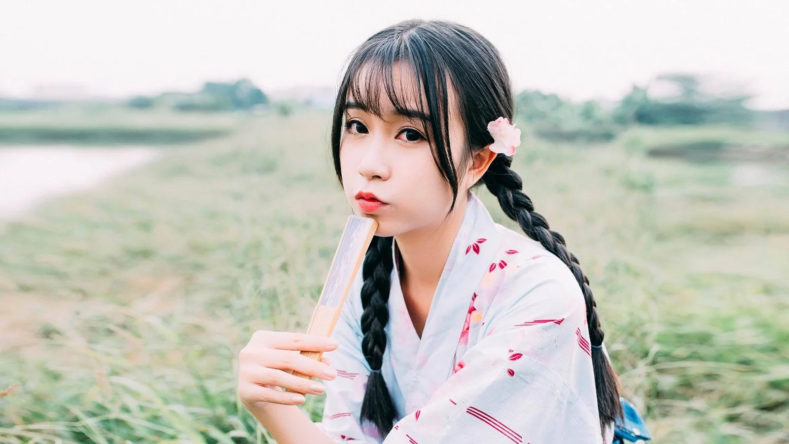 草地で三つ編みの女性がアイスキャンディーを手にしています。