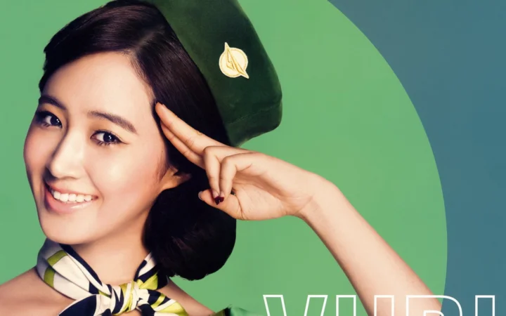 一名戴绿色贝雷帽、系彩色丝巾的女性在绿色背景前微笑并敬礼。