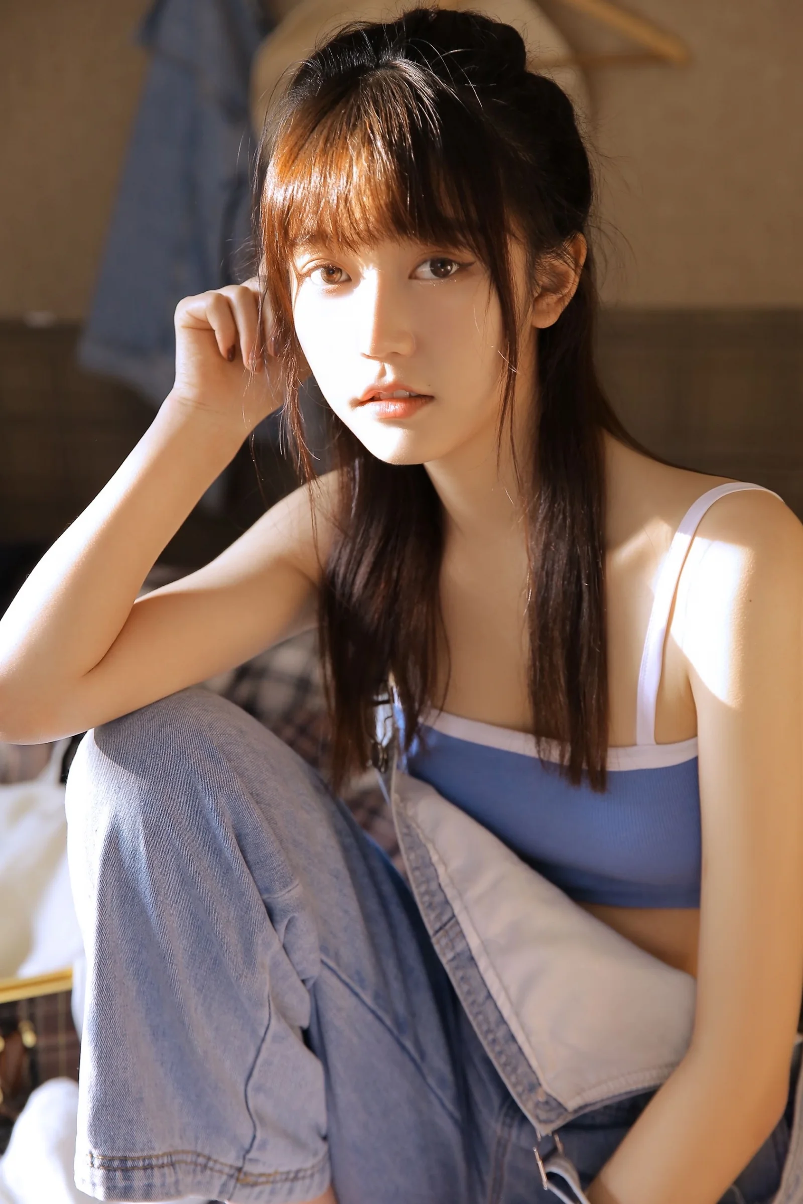 一位长发女性坐在室内，阳光从侧面照亮她的脸庞。