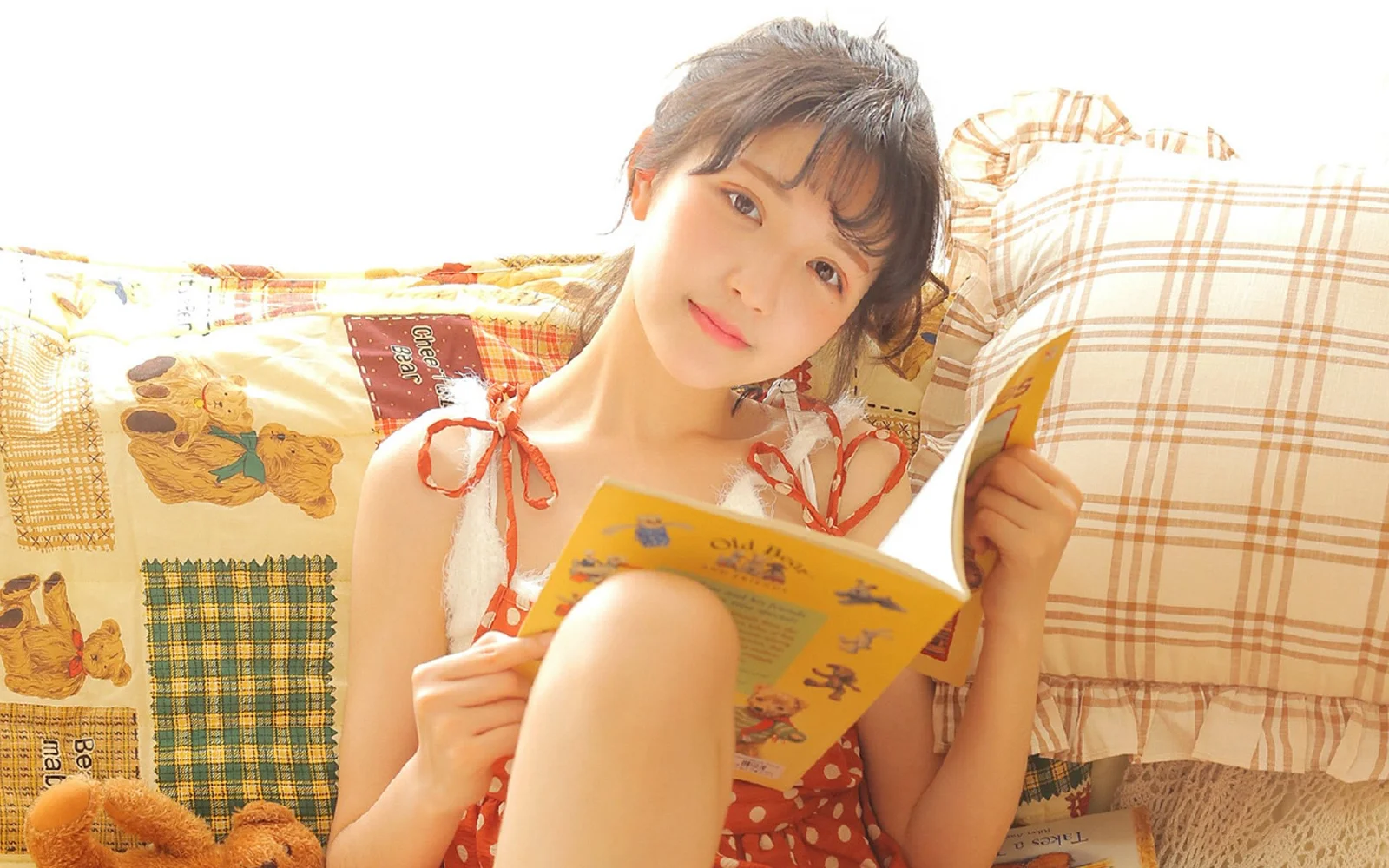 一名女性坐在床上閱讀一本彩色書籍。