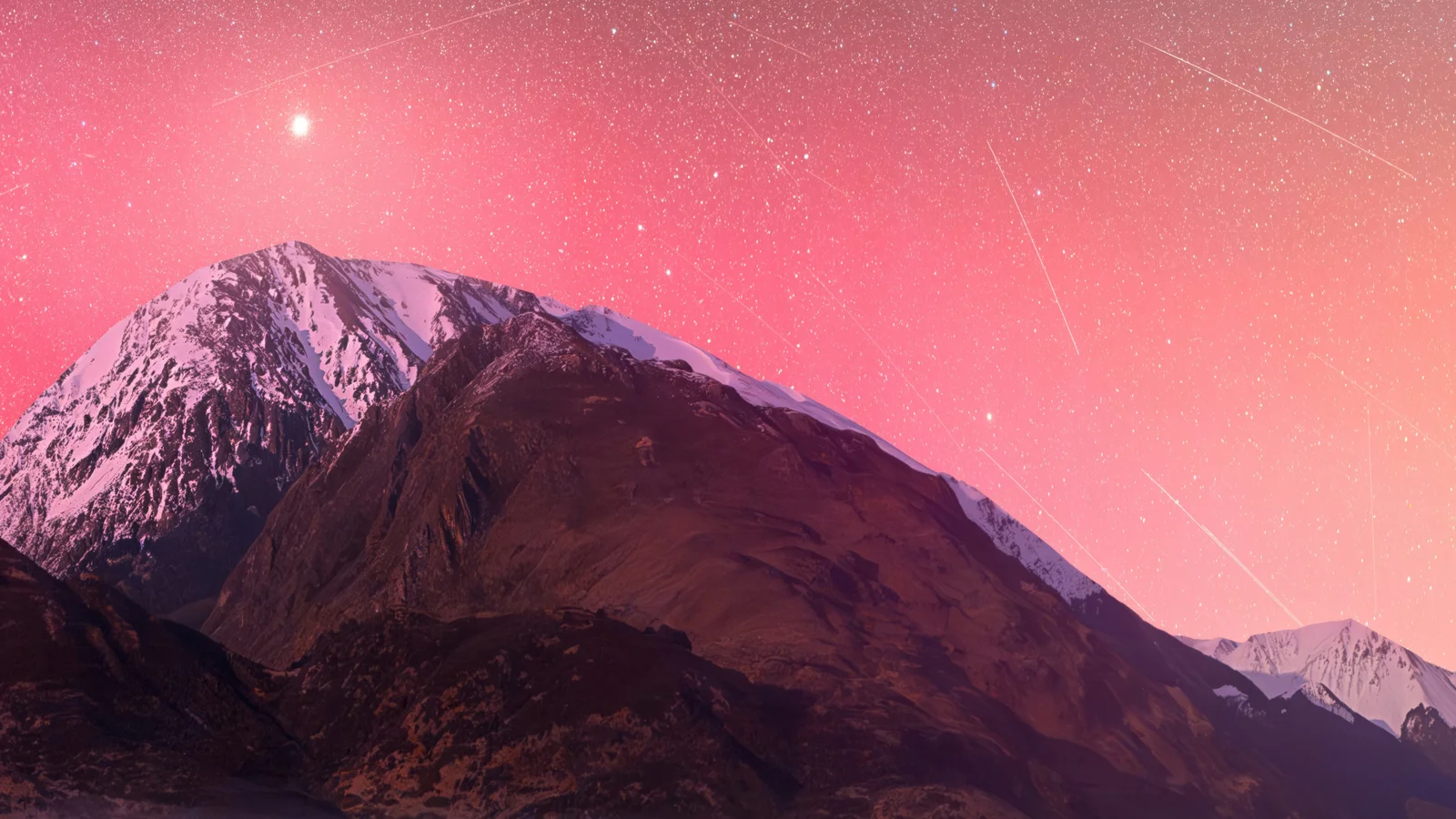 ピンク色の星空の下に、雪を抱いた山々と暗い尾根が連なっています。
