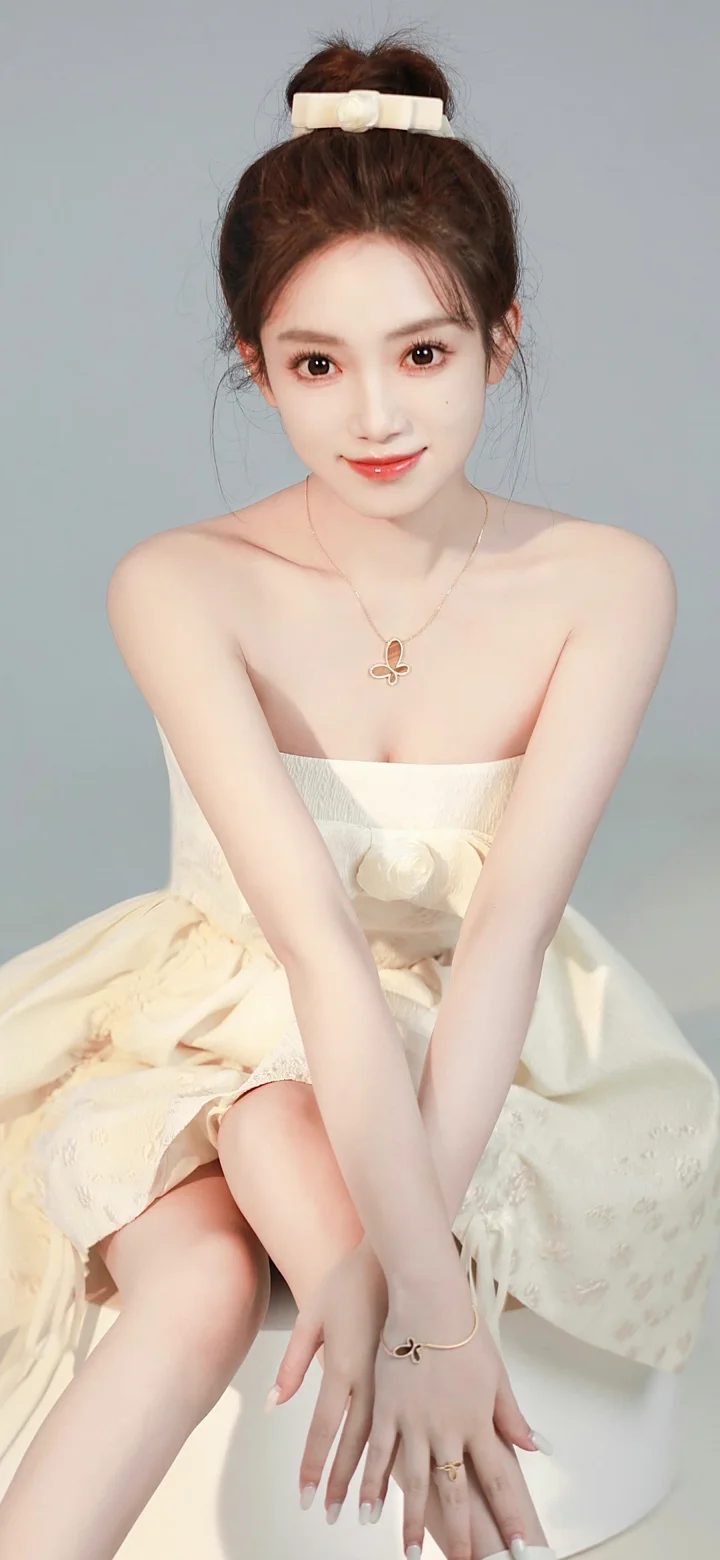 一名身穿白色无肩带连衣裙的女性坐在浅灰色背景前。