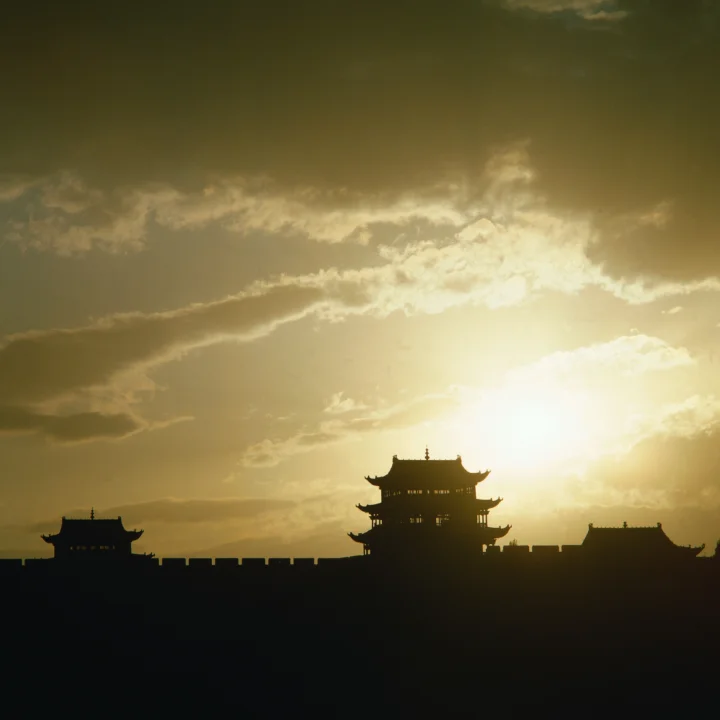 夕阳映照下，一座古建筑群呈现出深色剪影。