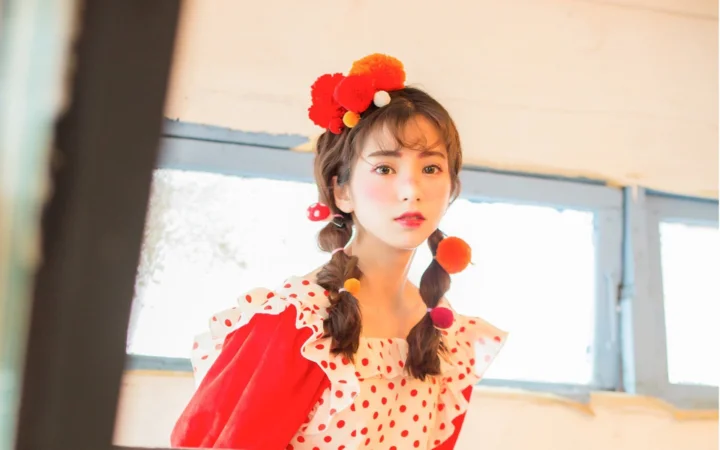 一位扎着双辫、佩戴红色发饰并穿着红白波点服装的女性面对镜头。