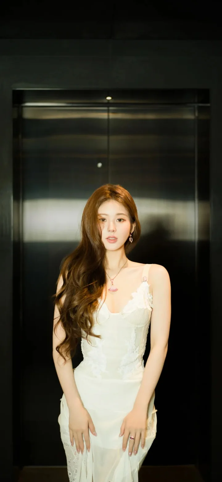 一名成年女性身穿白色连衣裙站在电梯内。