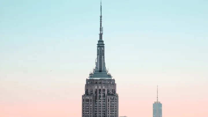 一座高耸的城市摩天大楼映衬在蓝粉色渐变天空下。