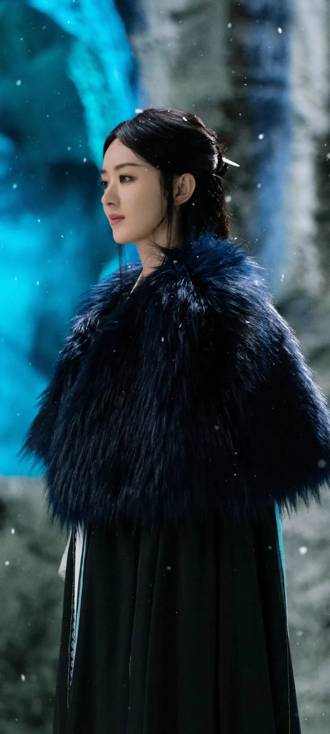 一名女子穿著黑色外套站在飄雪的戶外。