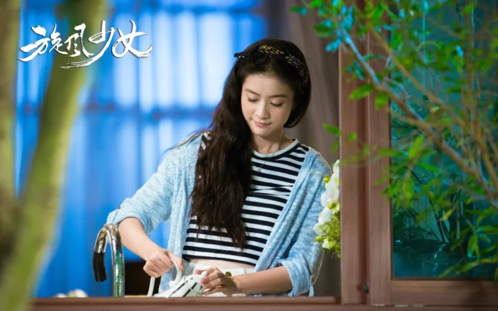 一名女子站在窗边的水槽旁低头处理物品。
