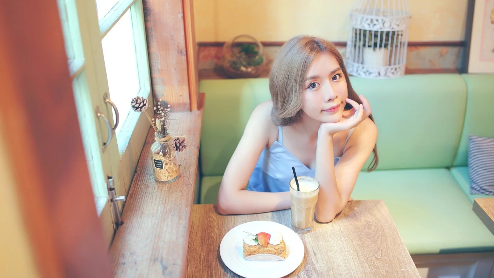 성인 여성이 음료와 음식 접시가 놓인 카페 테이블에 앉아 있다.