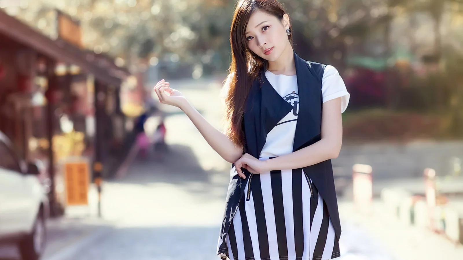 一名成年女性穿着黑白条纹裙站在户外街道上。