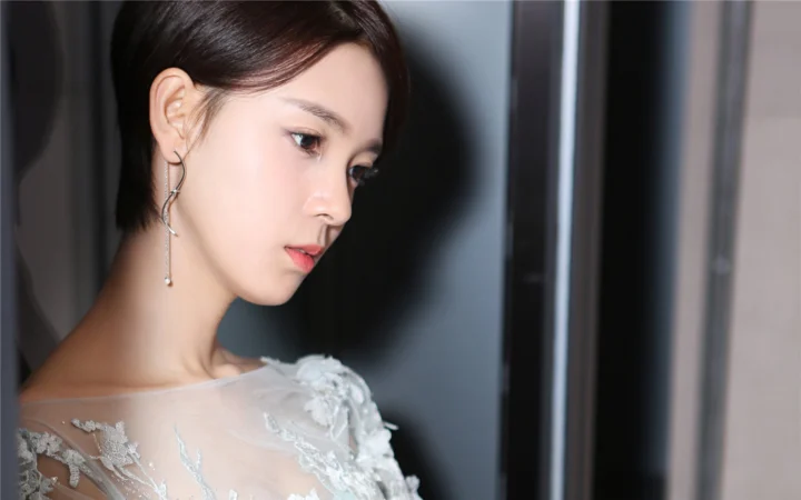 一位身穿白色蕾丝服装的女性在室内以侧面姿态呈现肖像。