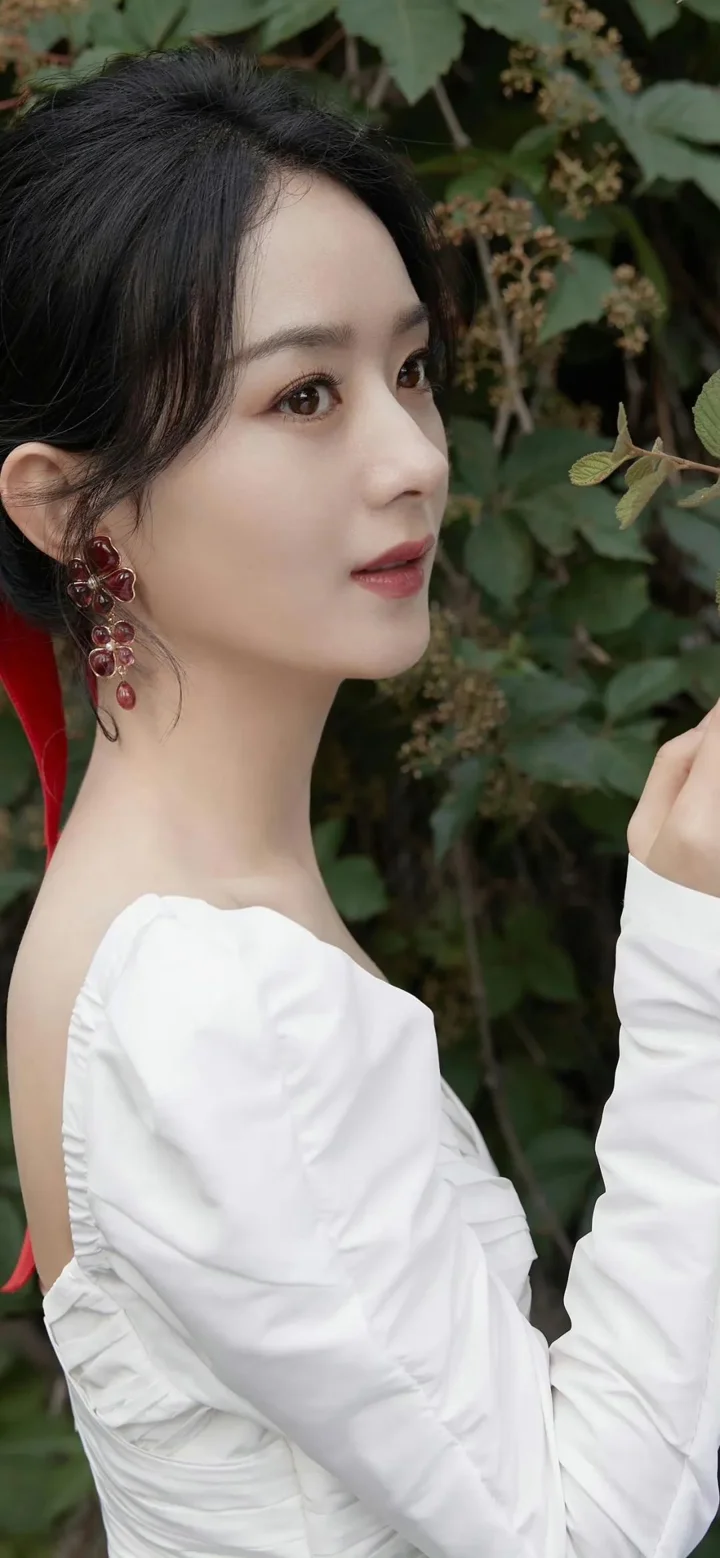 白いドレスを着た成人女性が、緑の葉を背景に横顔を見せています。