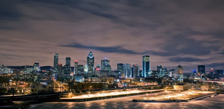 夜幕下的城市天际线灯火通明，前景道路与桥梁延伸至高楼之间。