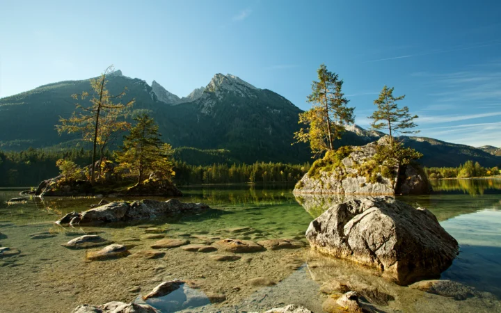 清澈的湖水映照着远处山脉、森林和湖中的岩石小岛。