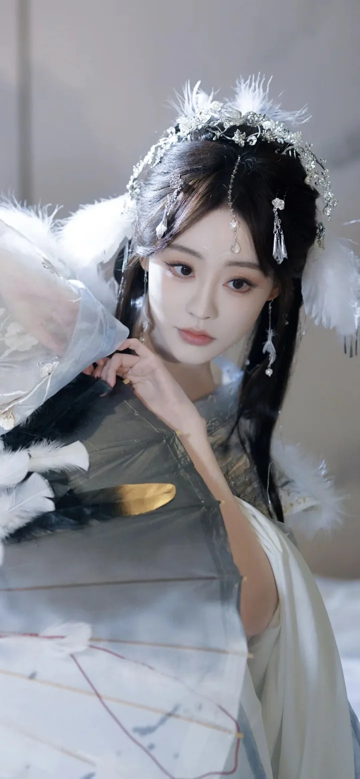 一名身穿传统服饰、佩戴华丽羽饰头冠的女子面对镜头摆姿势。