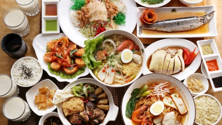俯视可见多盘面条、米饭、海鲜、鸡肉和配菜摆放在桌面上。