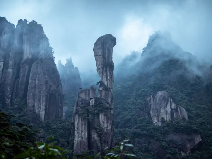 云雾缭绕的山林中矗立着壮观的岩石峰柱。