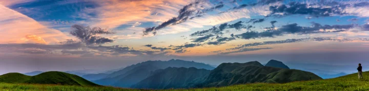 晚霞映照着层叠群山，远处天空布满舒展的云彩。