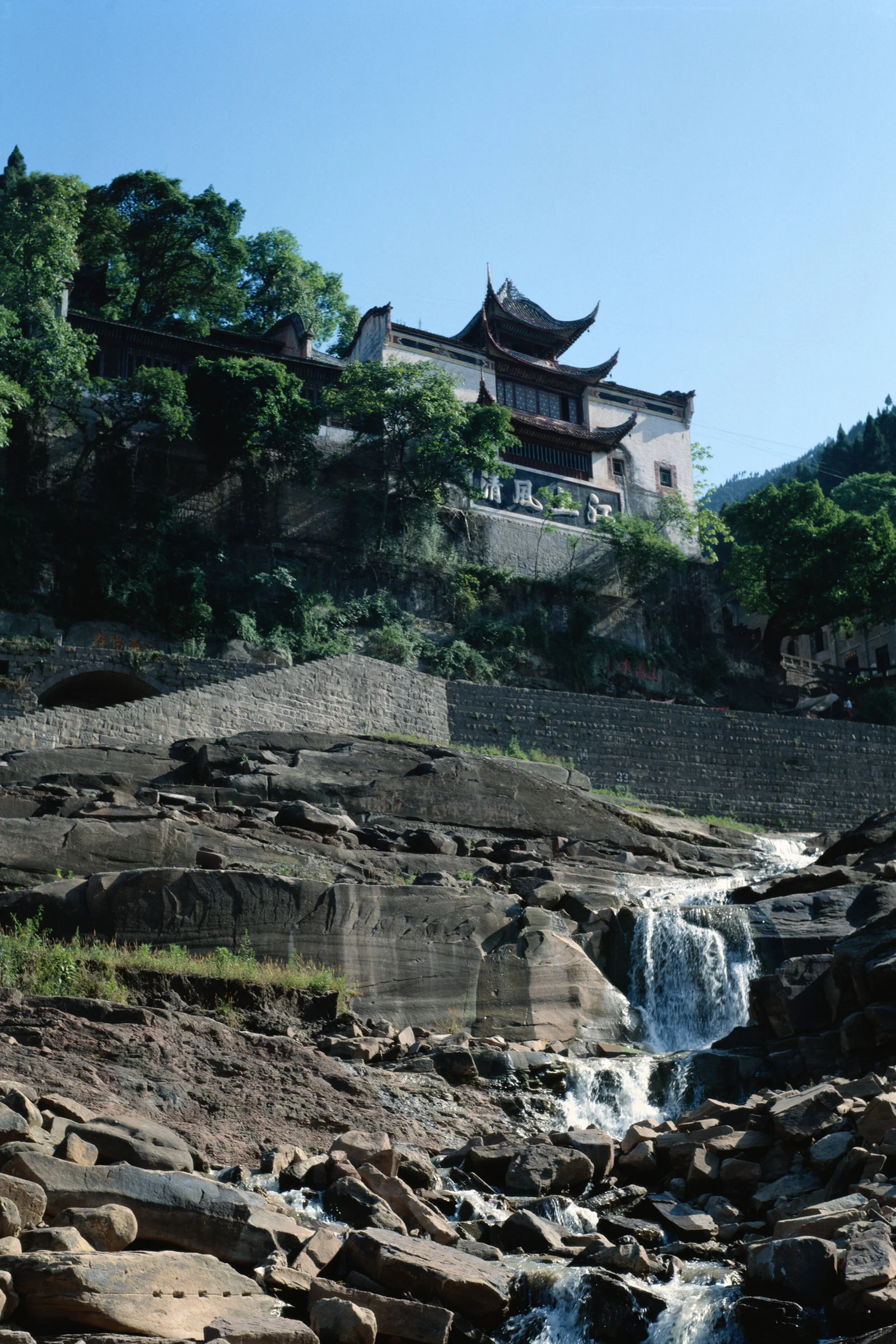 山间传统建筑坐落在树林与岩石溪流瀑布之上。
