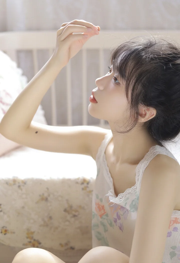 一名成年女性在室内柔和光线下抬手凝望，呈现侧面人像。