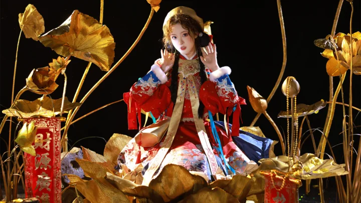 一名身穿红色传统服饰的女性坐在金色莲花装饰之间。
