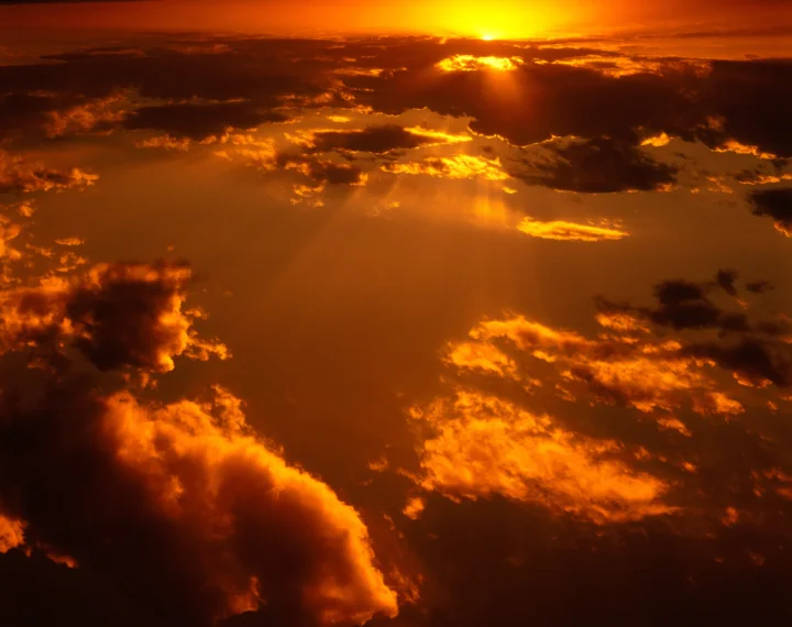 金色夕阳穿透翻涌的云层，映照出浓烈的橙红色天空。