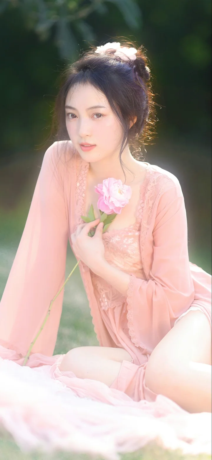 一名身穿粉色服装的女性在户外手持粉色花朵。