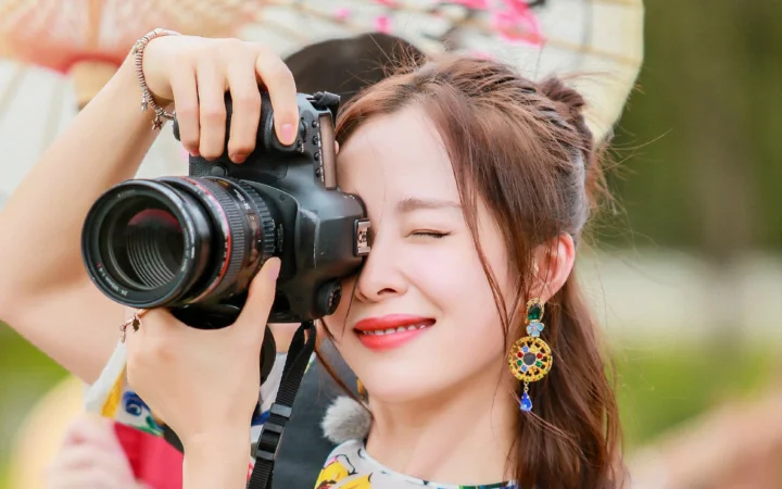 一名女性在户外手持相机拍摄。