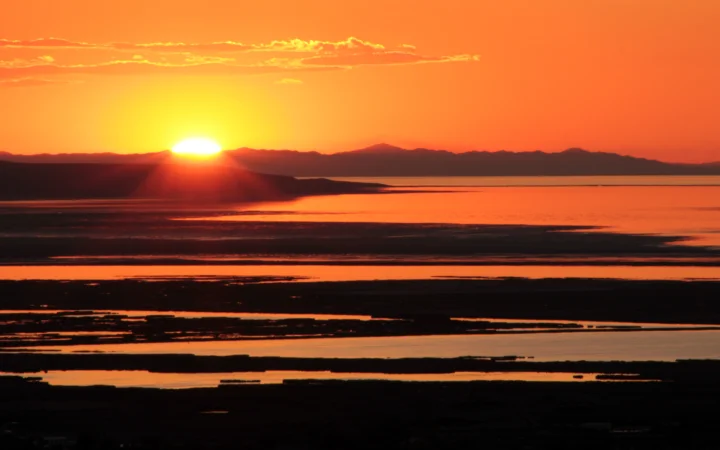 夕阳映照着远山与平静水面，形成橙红色的暮色景观。