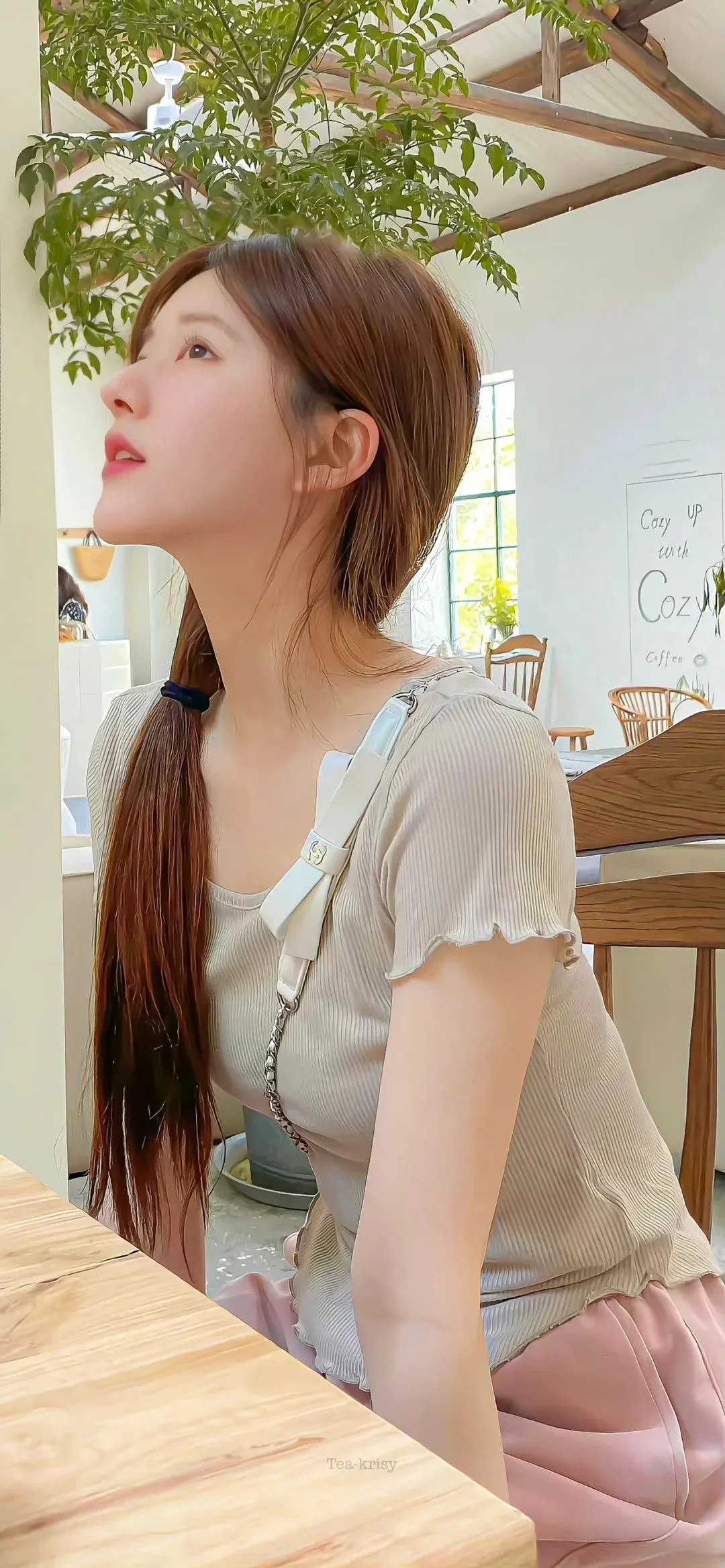 긴 포니테일을 한 성인 여성이 밝은 실내에서 옆모습으로 위를 바라보고 있습니다.
