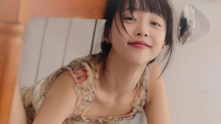 一位穿着花卉上衣的女性在室内靠近镜头微笑。