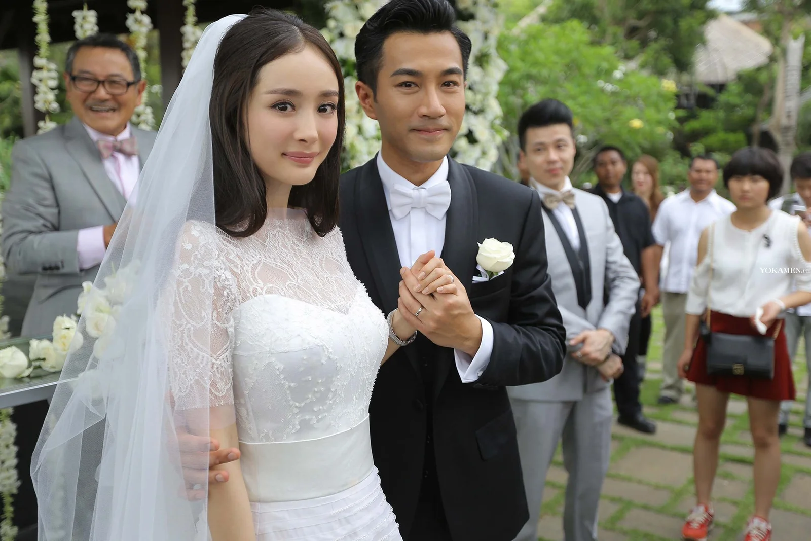 一对身穿婚礼服装的成年人在户外婚礼现场并肩站立。