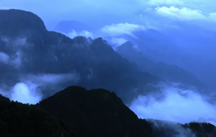 蓝色调的群山被云雾环绕，形成层叠的山景画面。