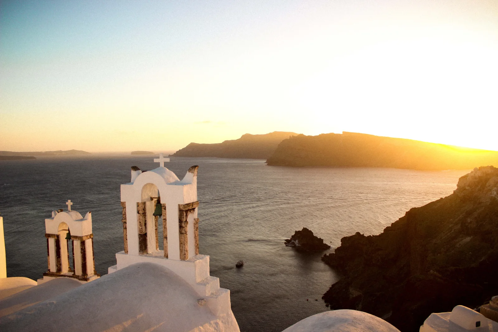 夕阳照耀着海面、远处的悬崖和前景中的白色钟楼建筑。