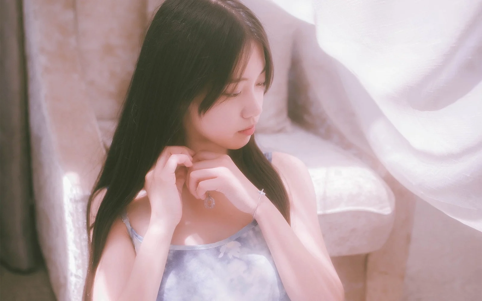 一位长发女性在室内柔和窗光下侧身整理头发。