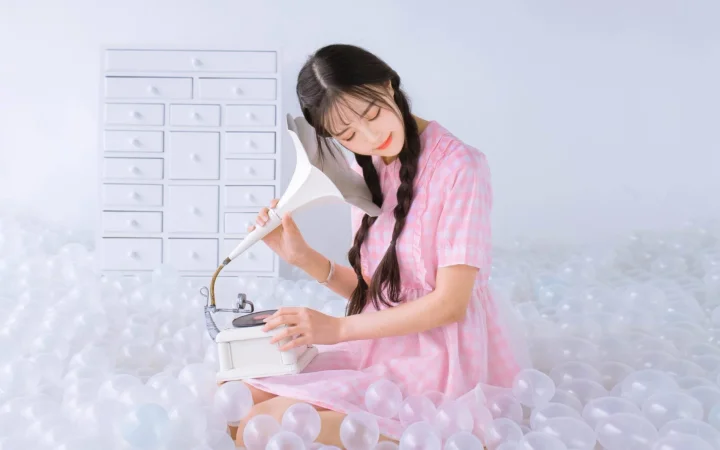 ピンクのドレスを着た女性が白い泡の中でミシンを操作しています。